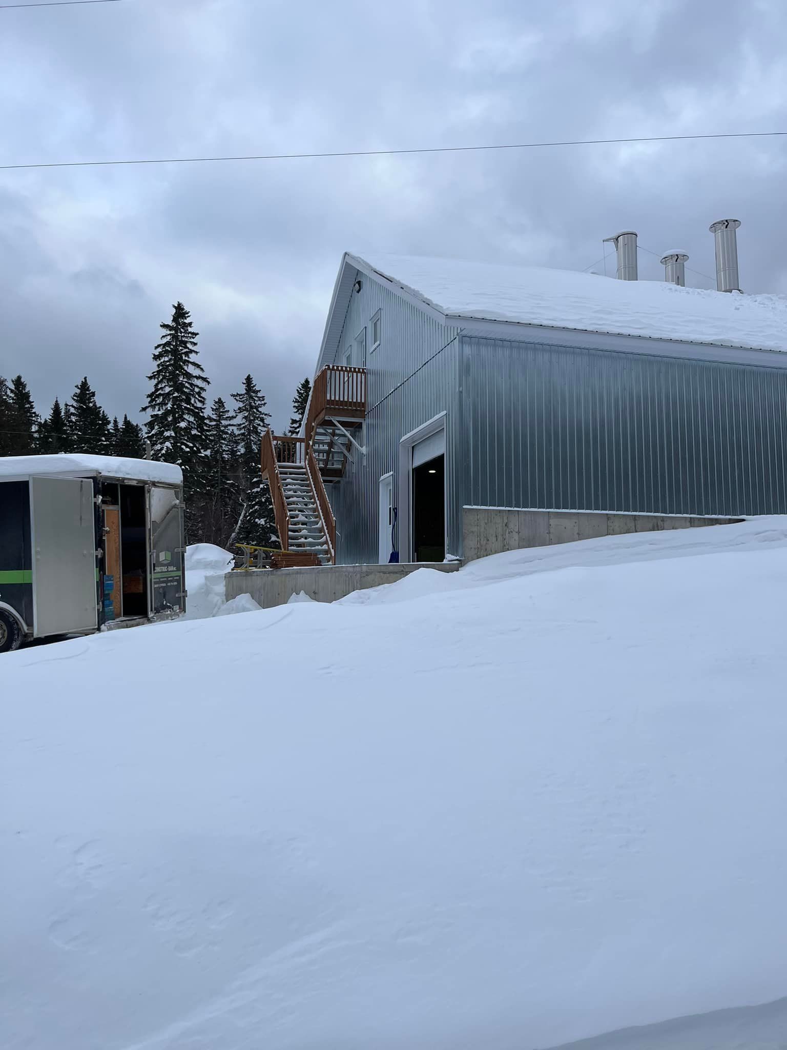 Un grand bâtiment recouvert de neige avec une remorque garée devant