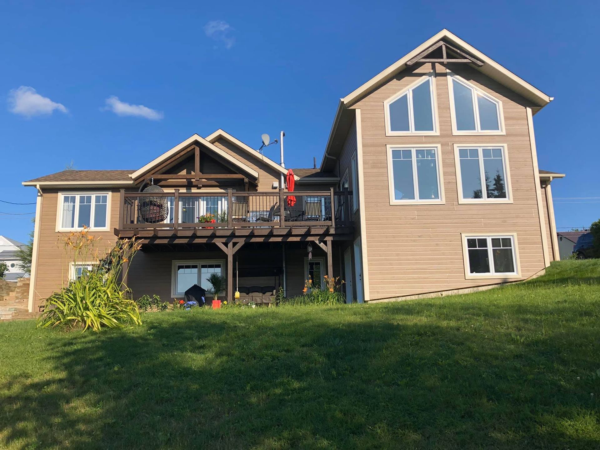 Une grande maison est située au sommet d'une colline herbeuse.
