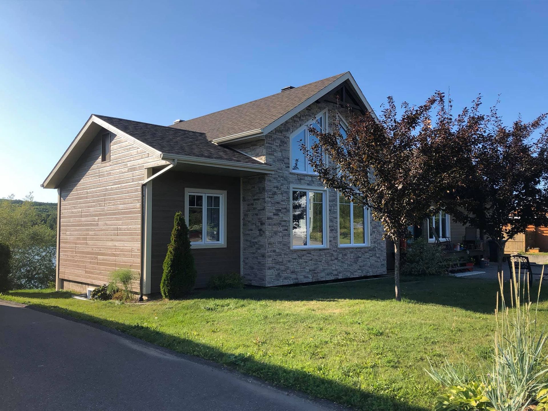 Une maison avec beaucoup de fenêtres et un arbre devant