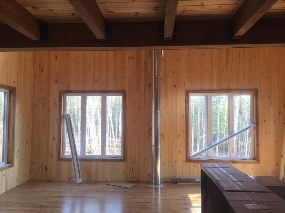 Une pièce en bois avec beaucoup de fenêtres et une cheminée.