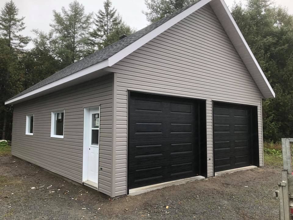 Un garage avec deux portes de garage noires et une porte blanche