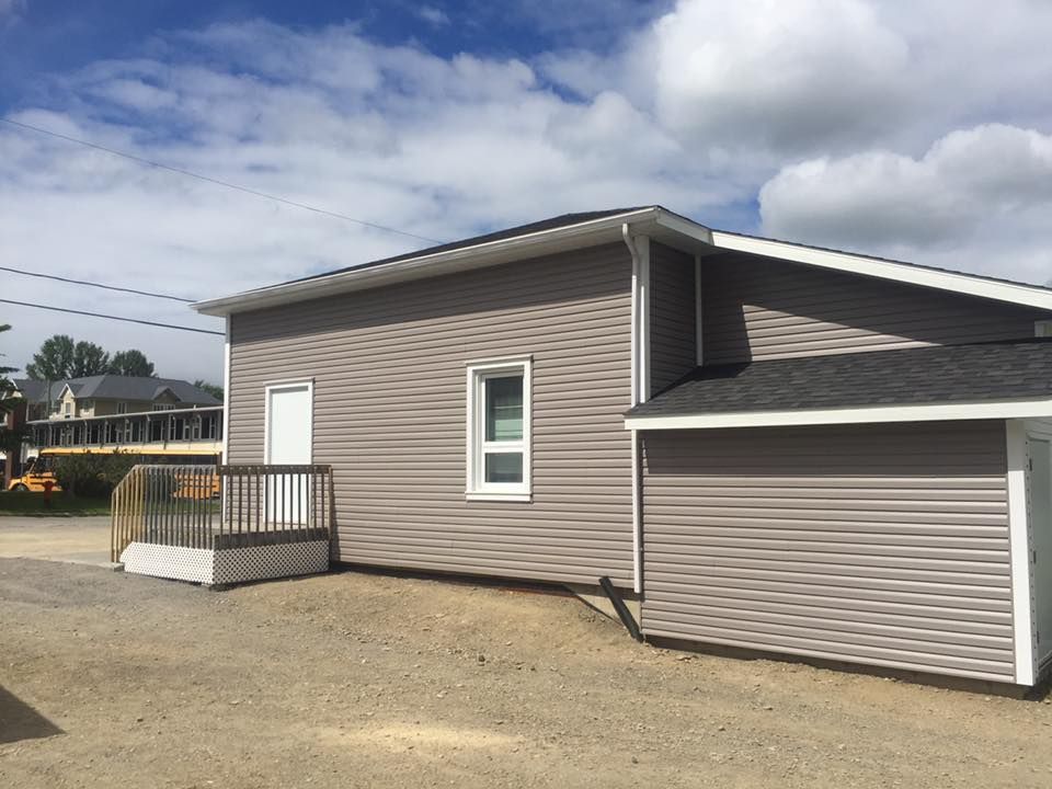 Une maison avec un revêtement gris et un toit noir