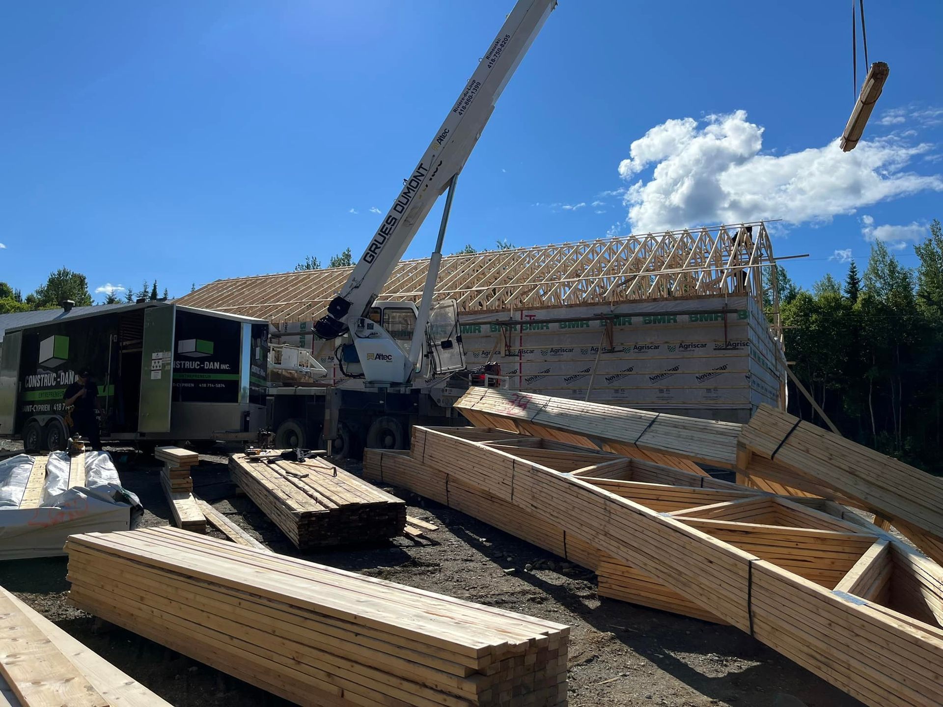 Une grue soulève un morceau de bois au-dessus d'un tas de bois.