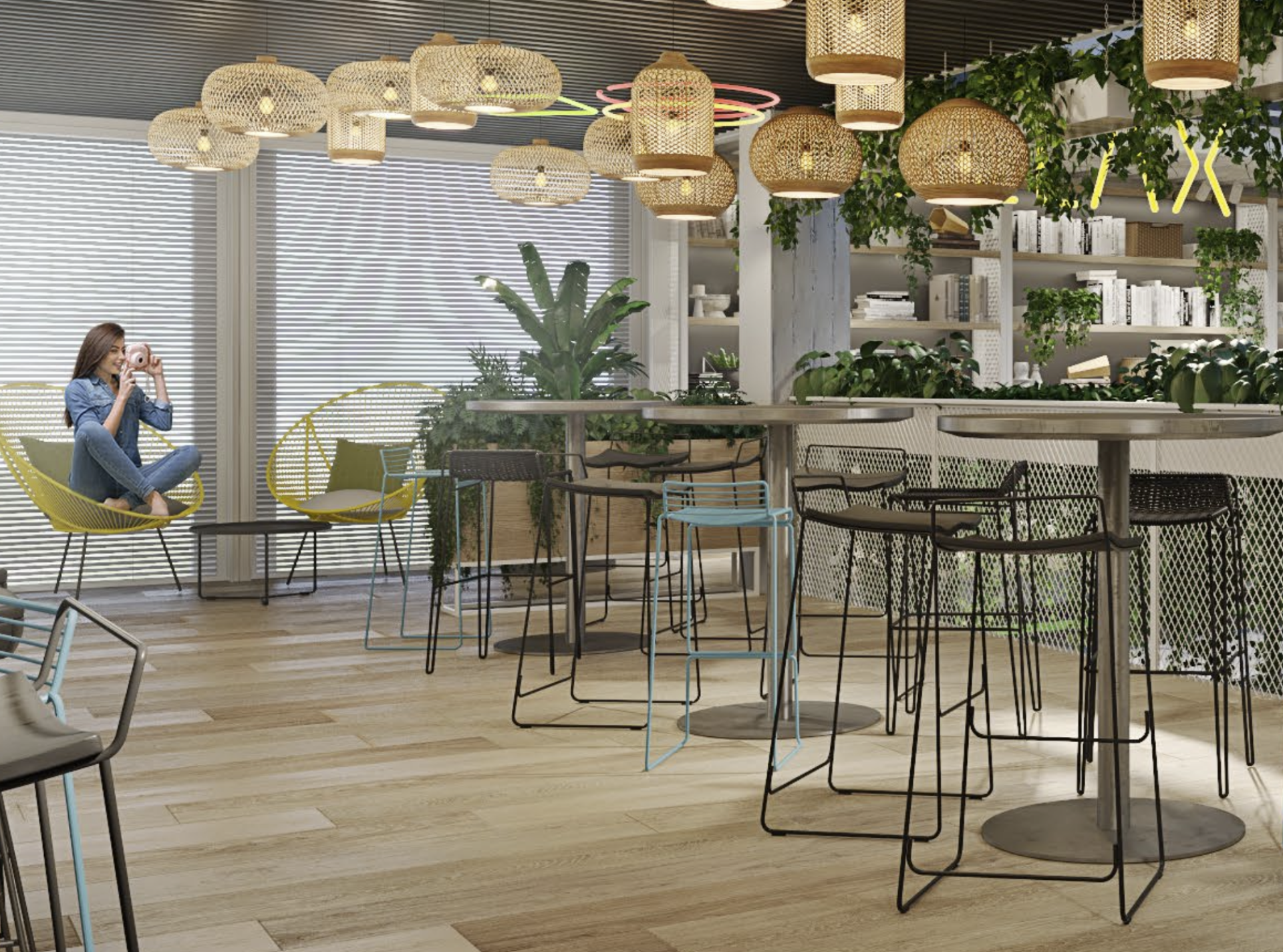 A cafe interior with rattan lamps, high-top tables, and a woman in a chair taking a photo.