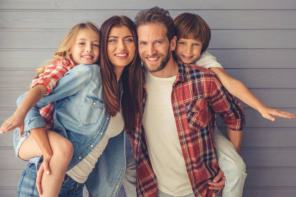 smiling mom and dad with kids on their backs