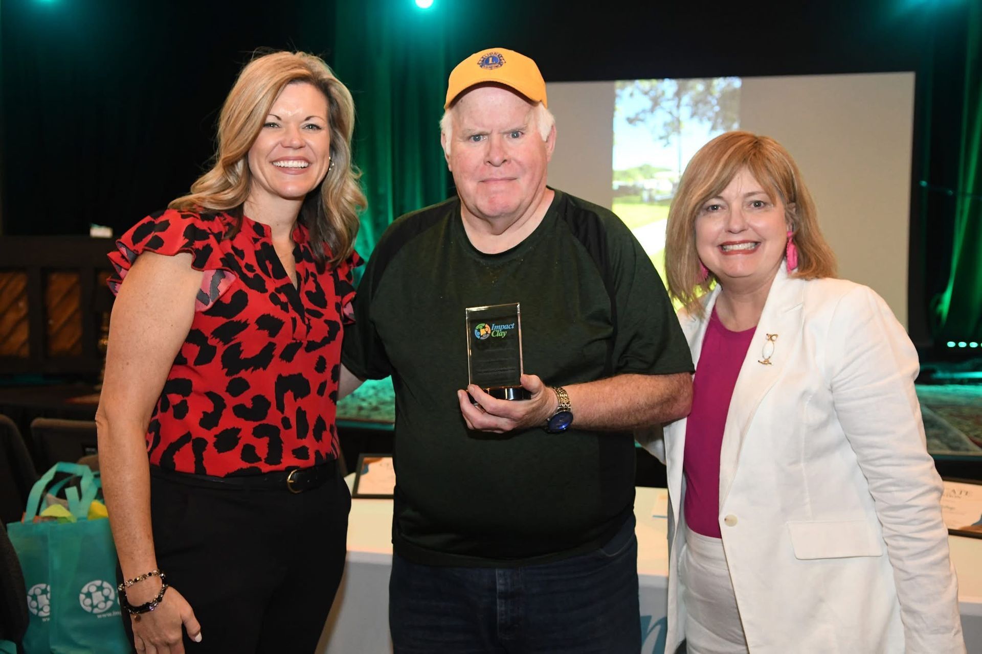 A man is holding a cell phone while standing next to two women.