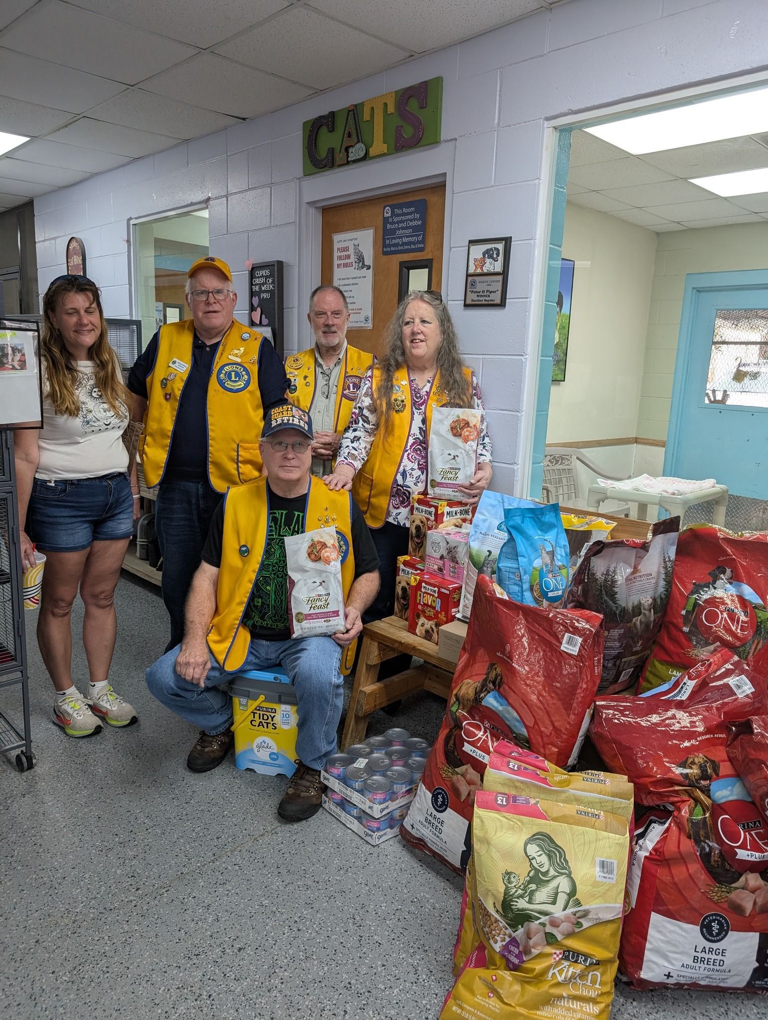A group of people are posing for a picture in front of a pile of dog food.