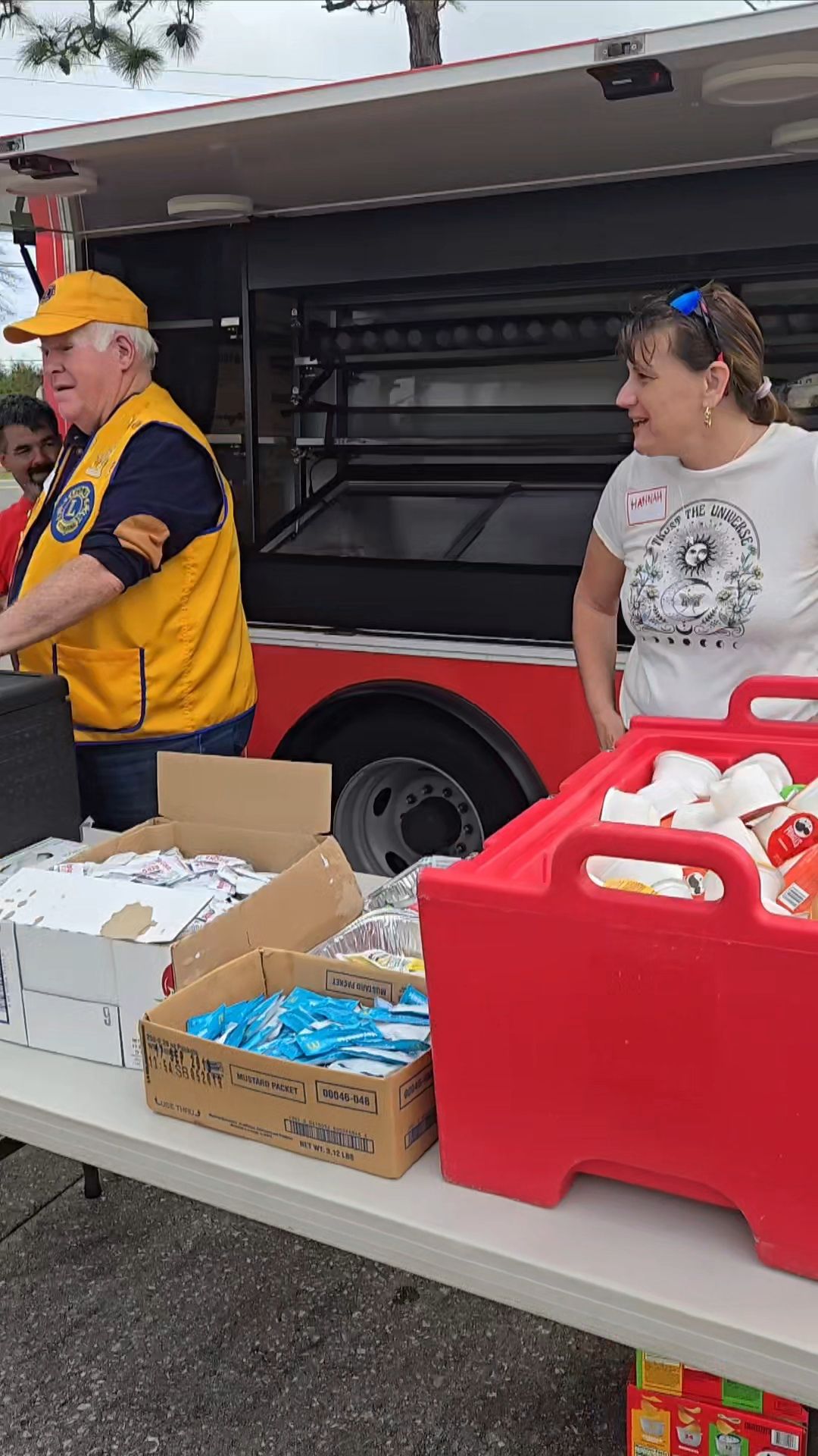 A man and a woman are standing in front of a food truck.