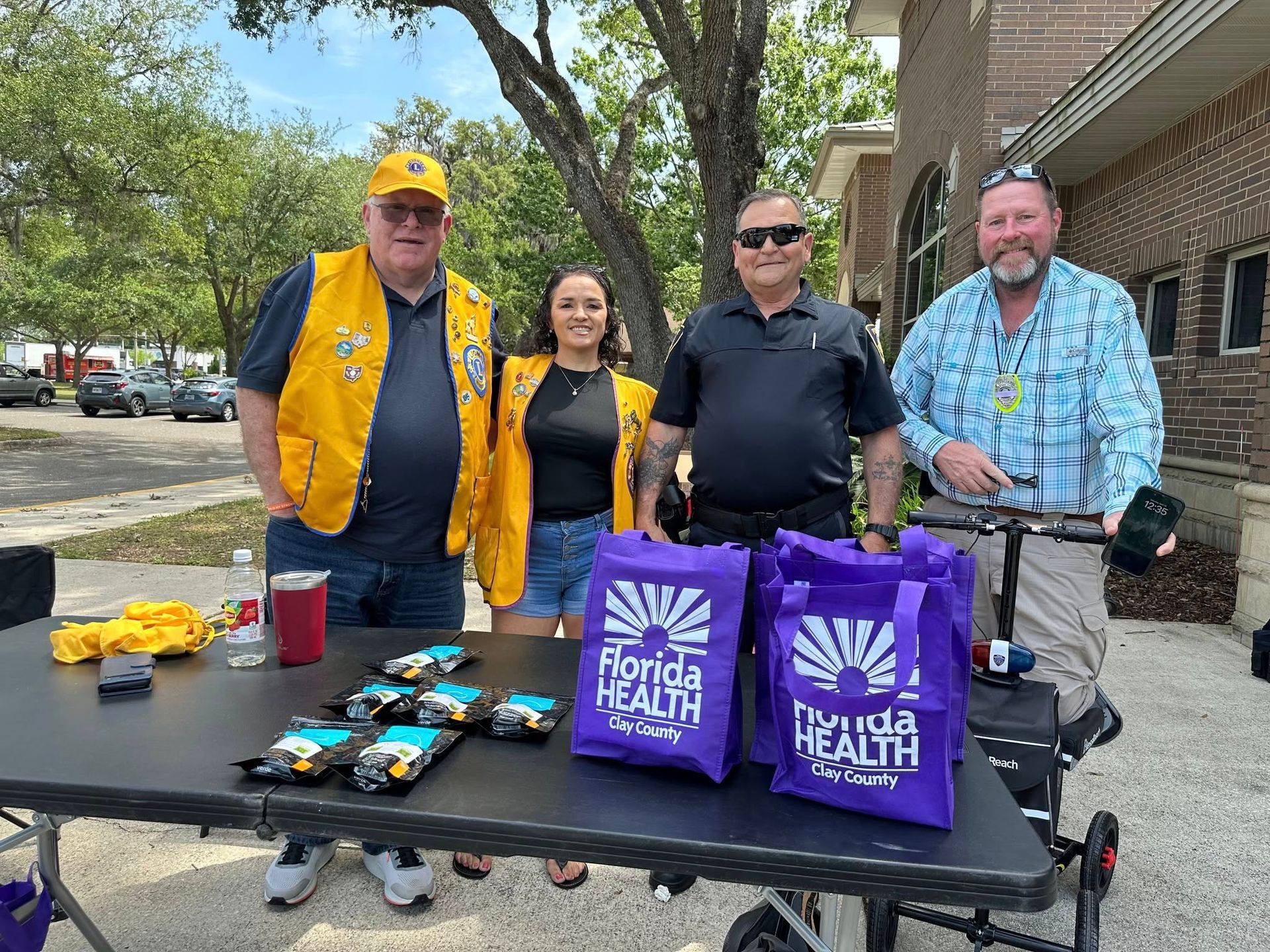 A group of people are standing around a table with purple bags on it.