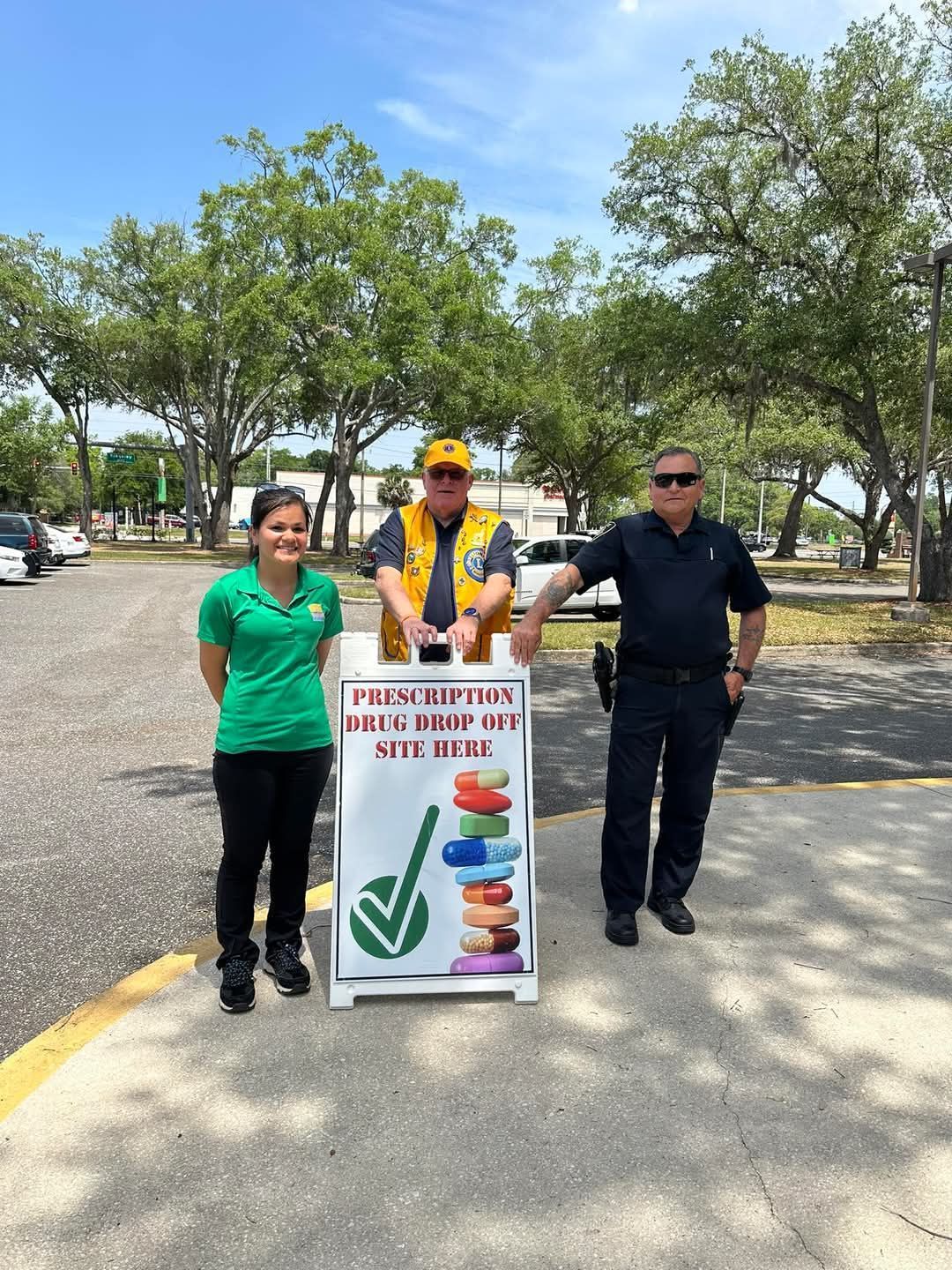 A group of people are standing next to a sign that says prescriptions on it.