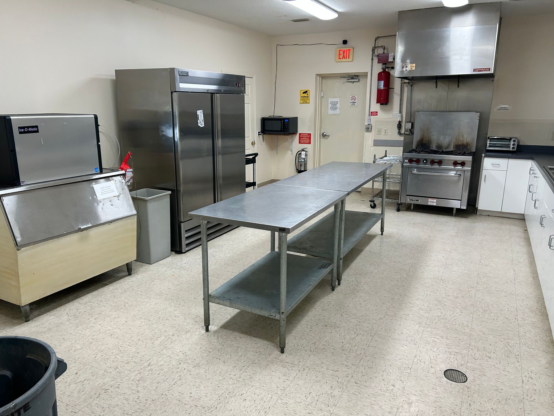 A kitchen with stainless steel appliances and a trash can