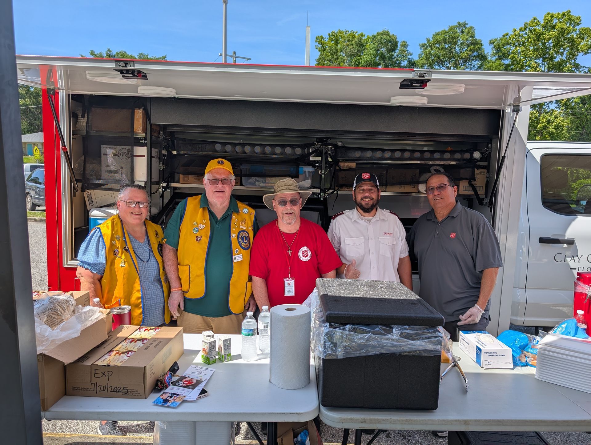 Five people, Red Cross volunteers, at a mobile food truck. They are smiling and ready to serve.
