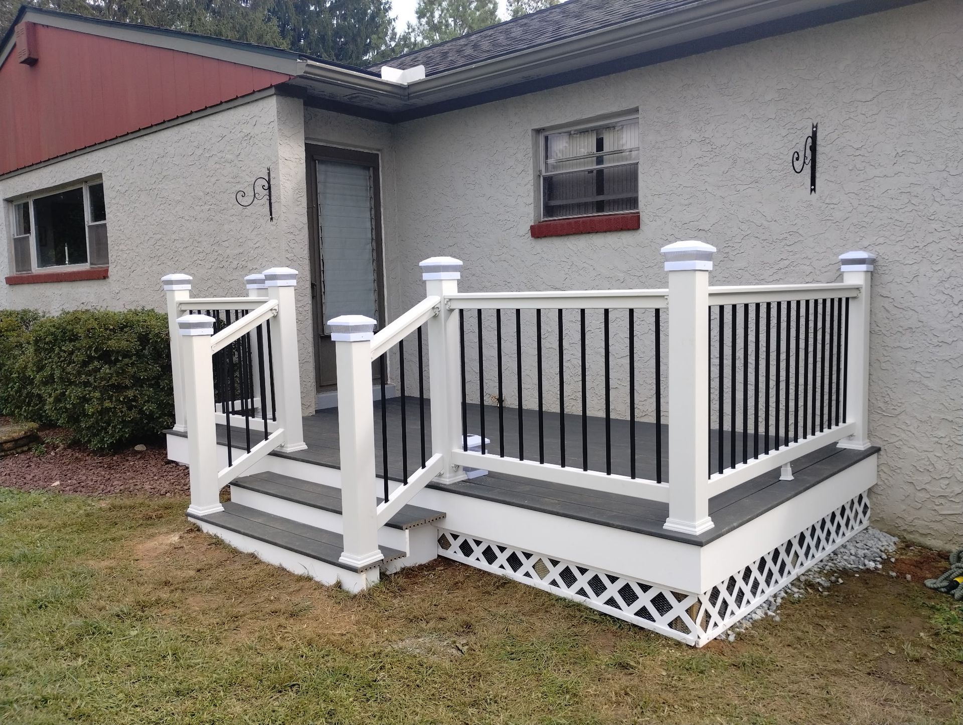 White deck with black railing and steps, in front of a stucco house.