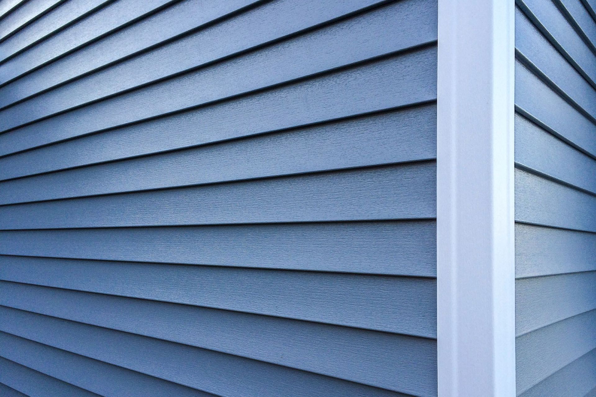 Blue siding on a building's exterior corner, with a white column in the corner.
