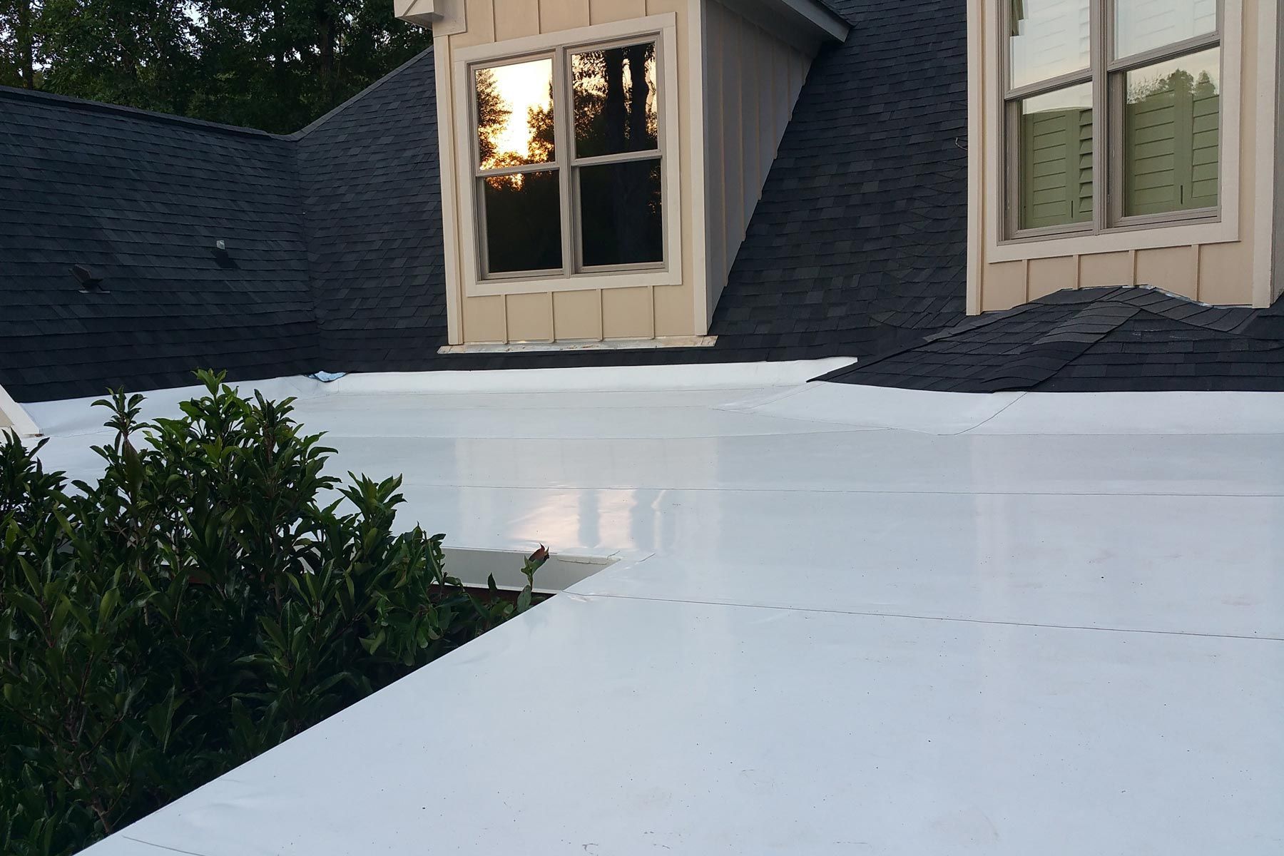 White flat roof with dormer windows against a dark roof.
