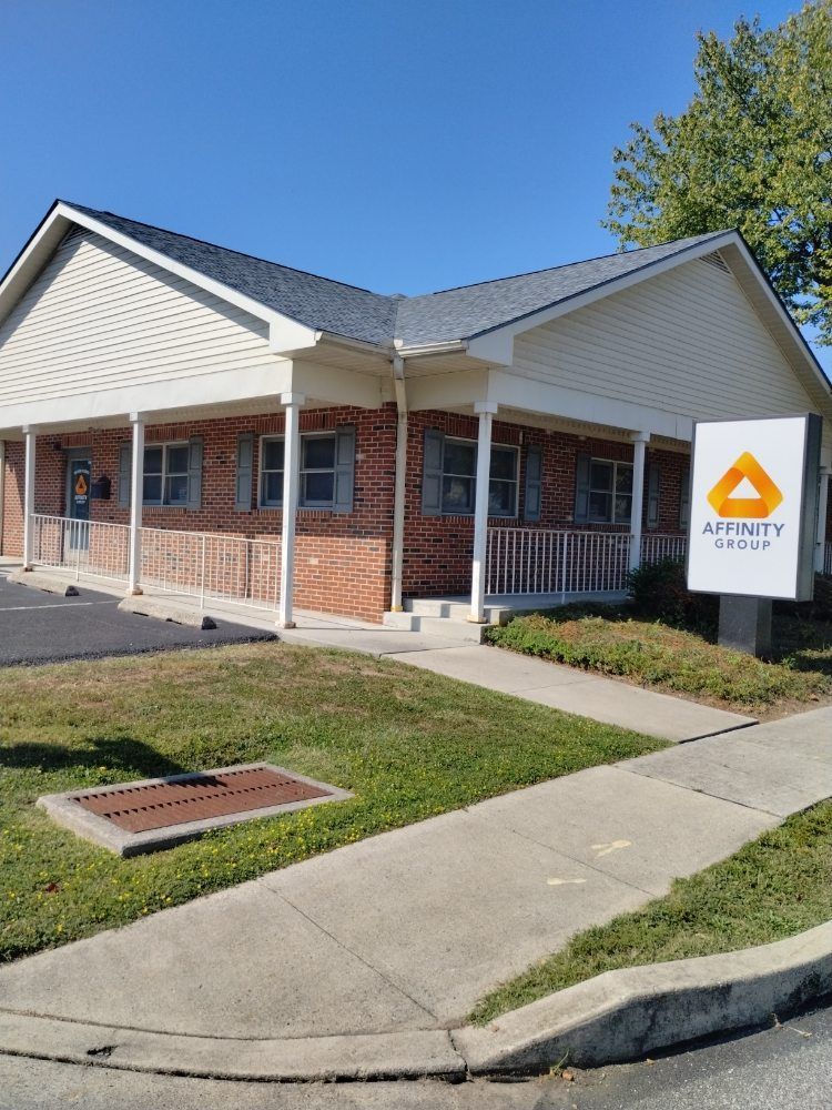 Affinity Group office building with brick facade and sign, green grass, clear sky.