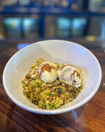 White bowl of food with two scoops, brown topping, on a wooden table. Blurred background.