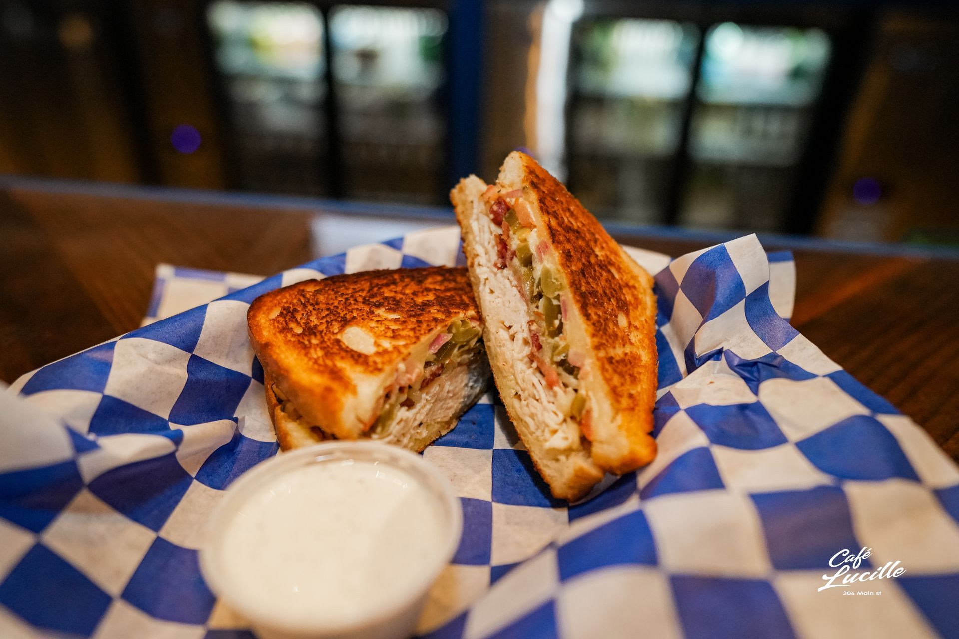 Grilled sandwich cut in half with dipping sauce, in a checkered basket.