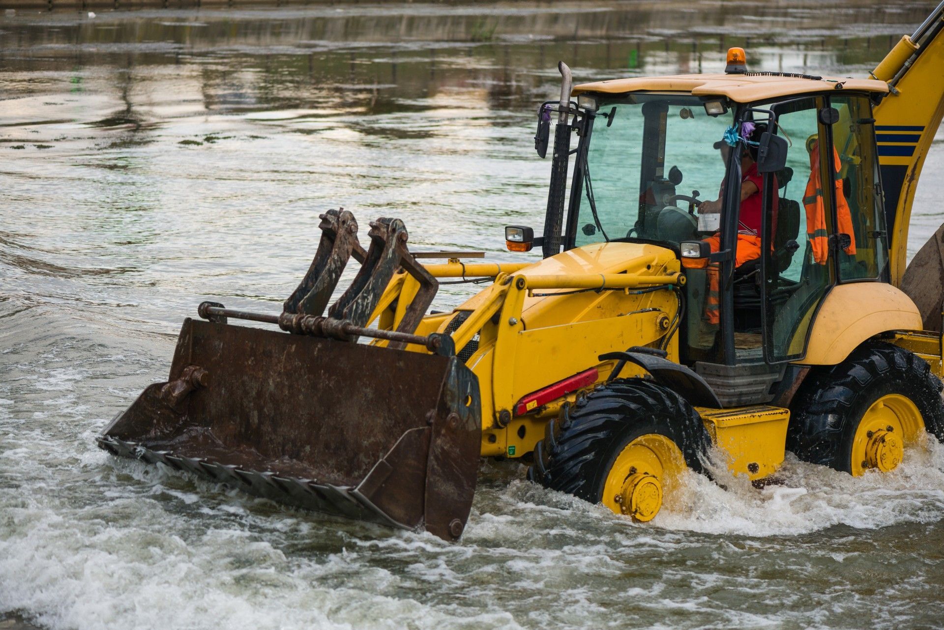 A yellow bulldozer is driving through a river.