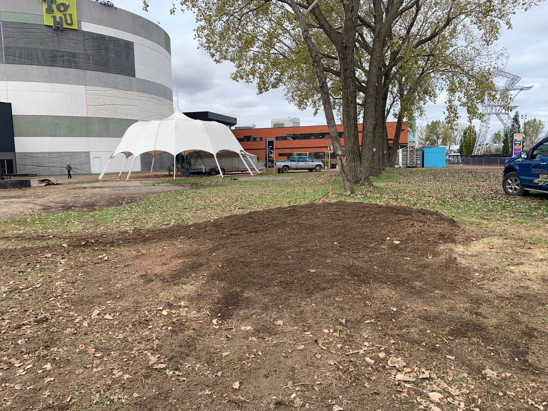 Une voiture bleue est garée dans un champ devant un bâtiment.