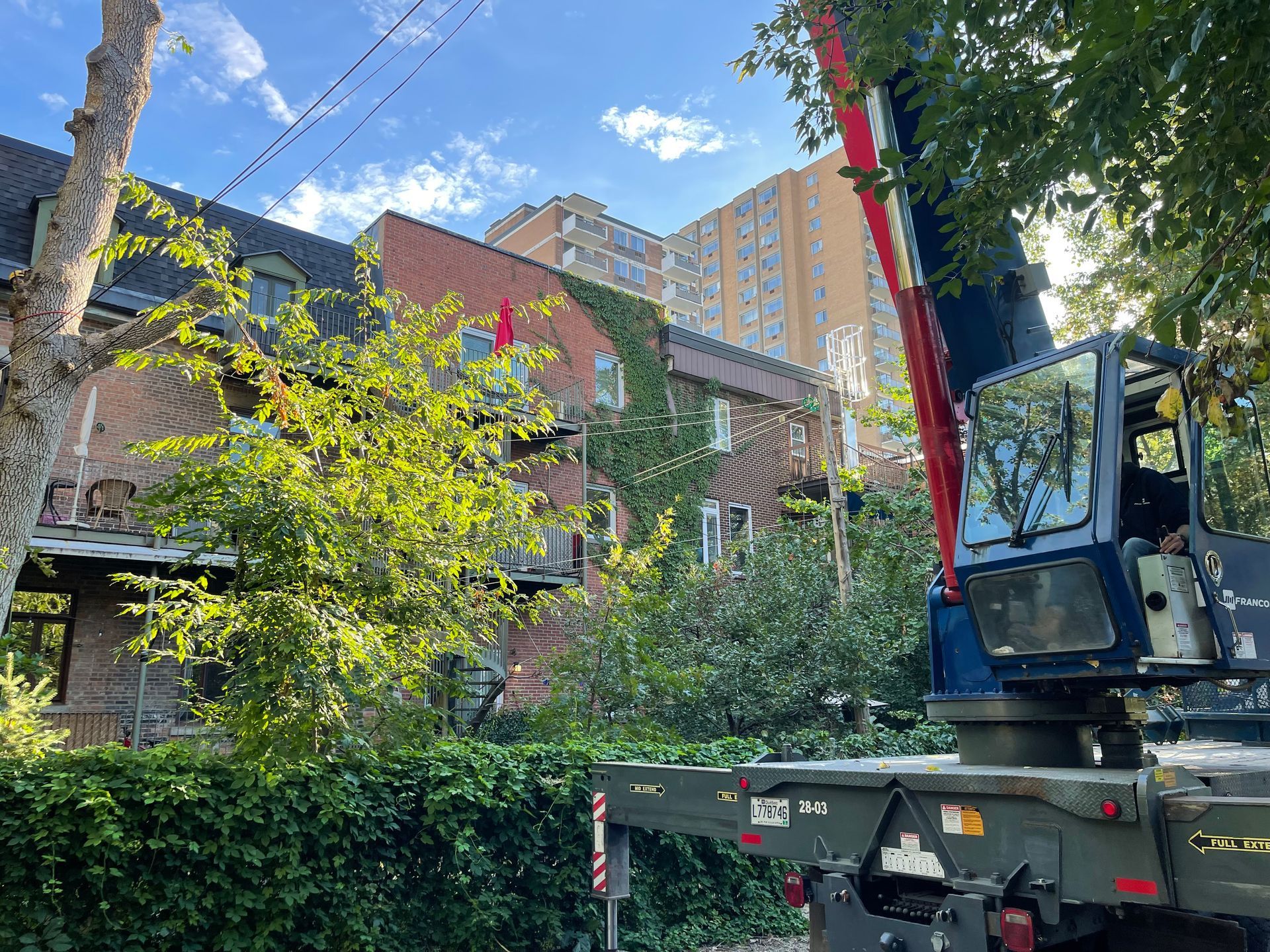 Une grue est posée sur un camion devant un bâtiment.