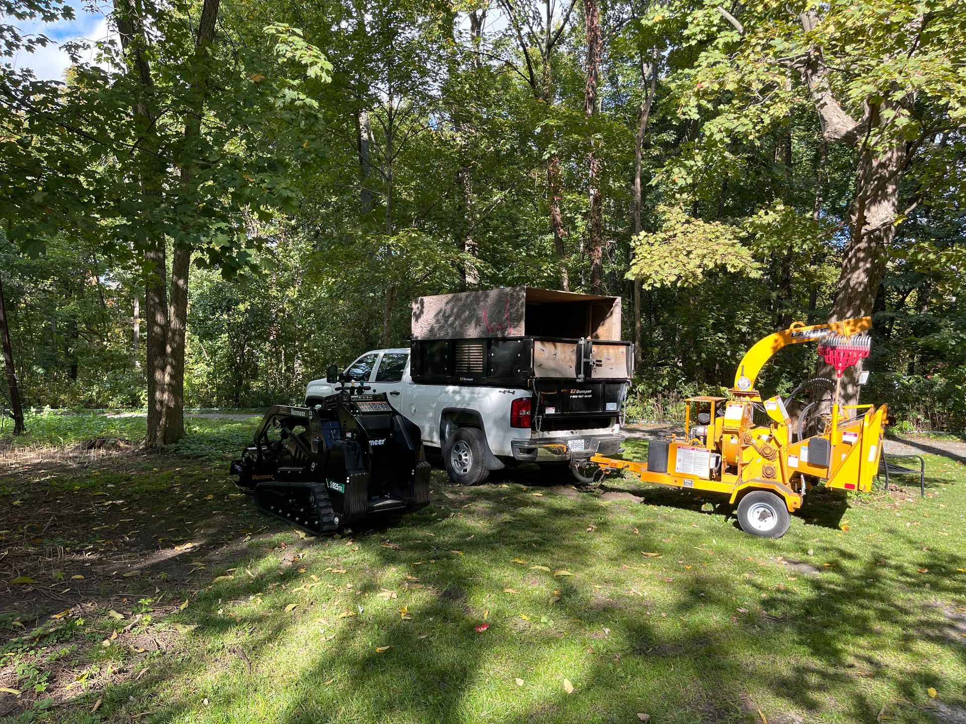Un camion est garé à côté d'un broyeur d'arbres dans les bois.