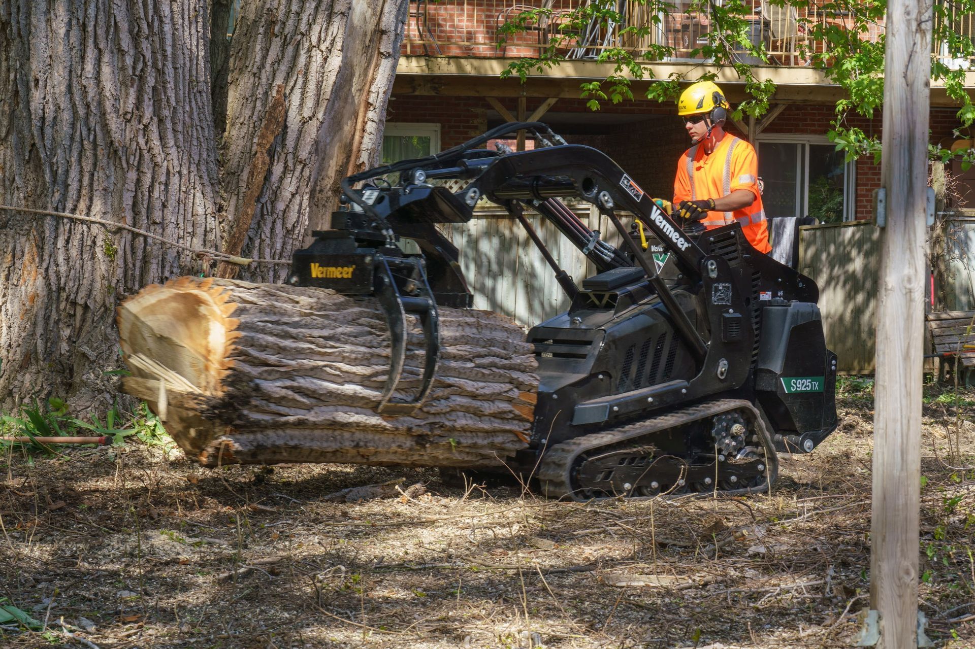 Un homme conduit un tracteur avec une grosse bûche à l'intérieur.