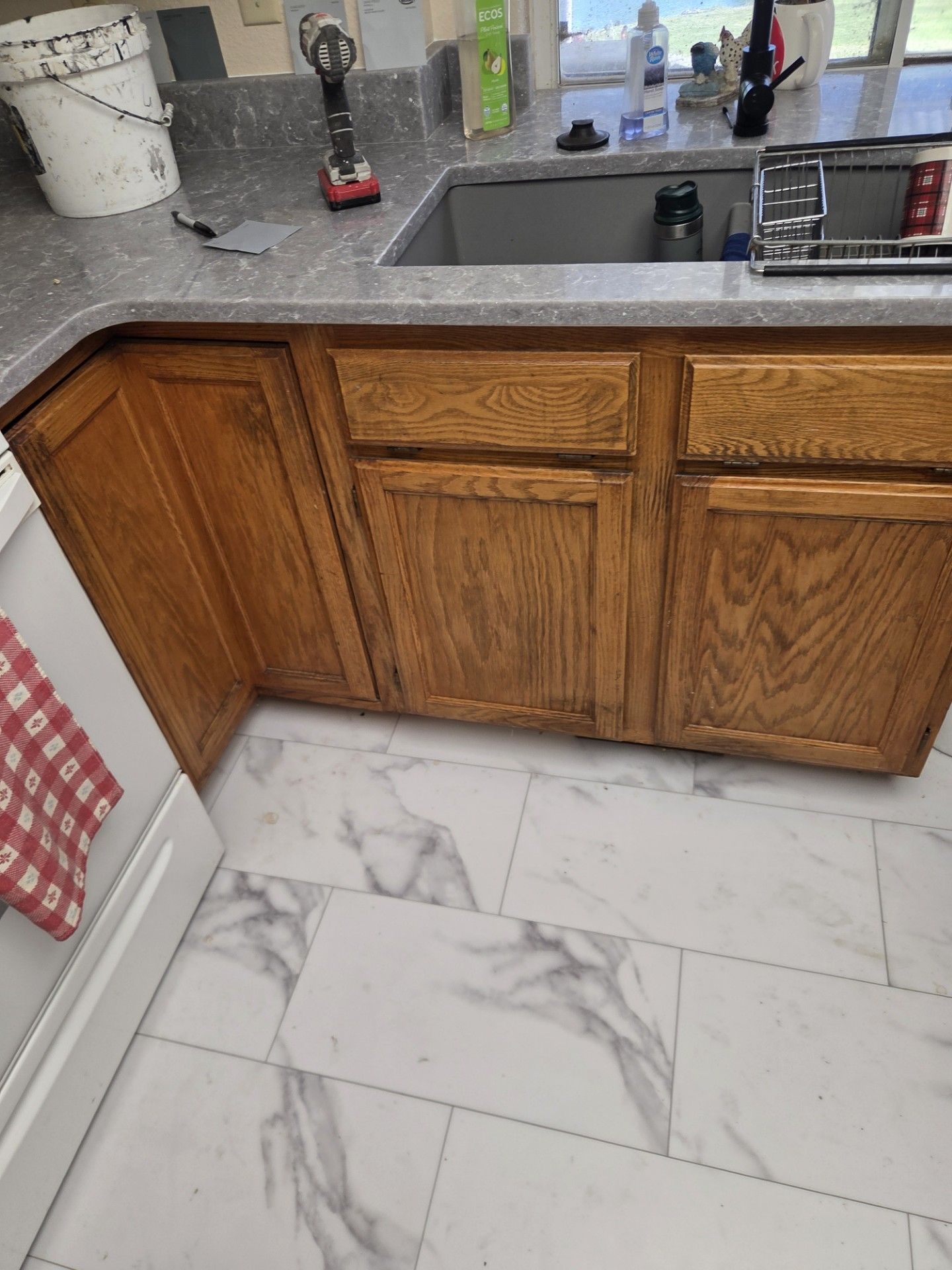 Wooden kitchen cabinets with a gray countertop, a sink, and marble tile flooring.