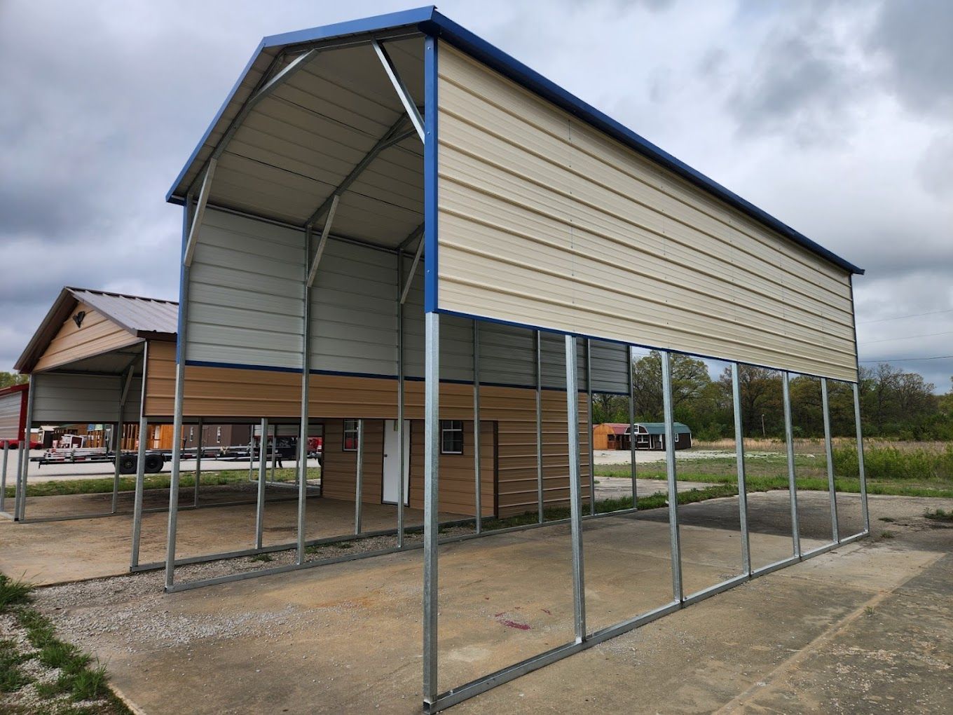 A metal building with a blue roof is sitting next to a house.