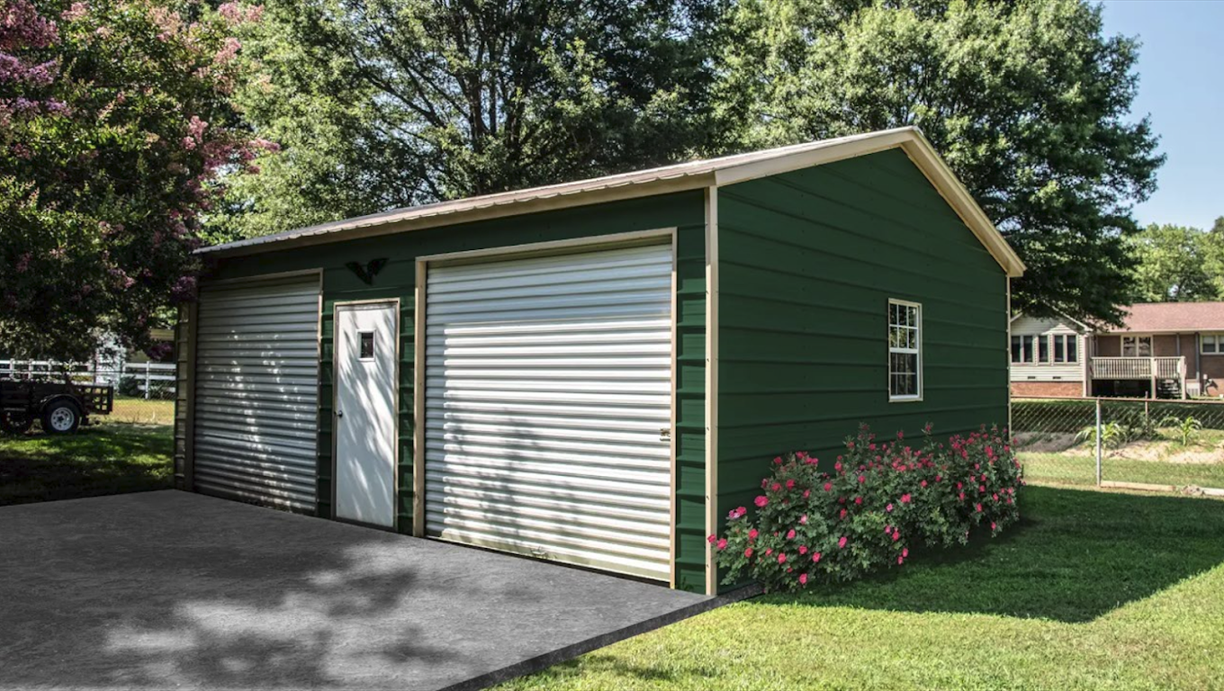 A green garage with two garage doors and a driveway in front of a house.