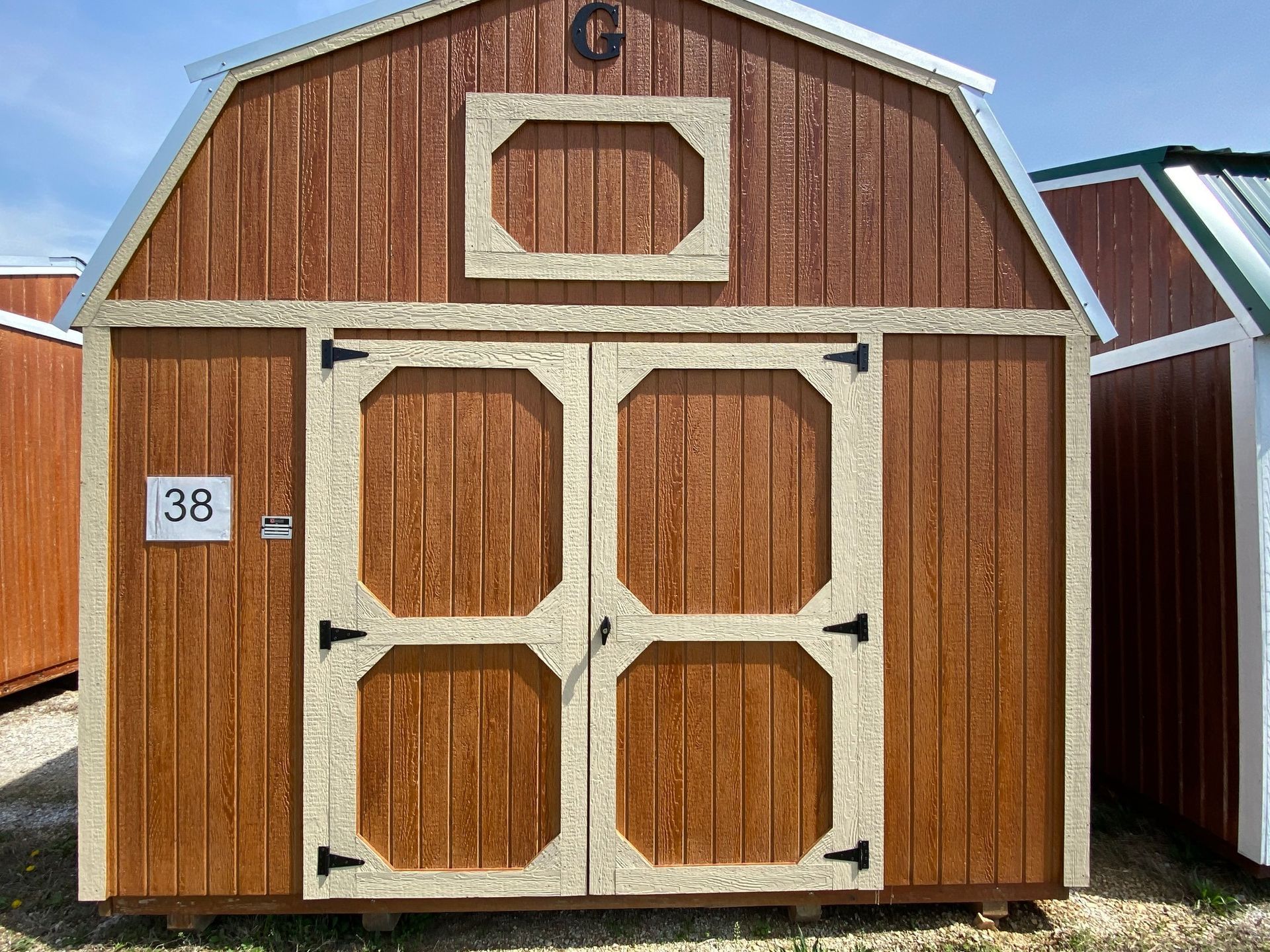 A barn shaped shed with two doors and a window.