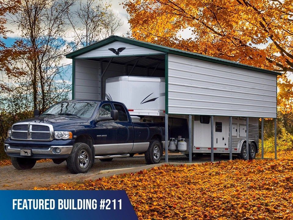 A truck is parked under a trailer in a carport.
