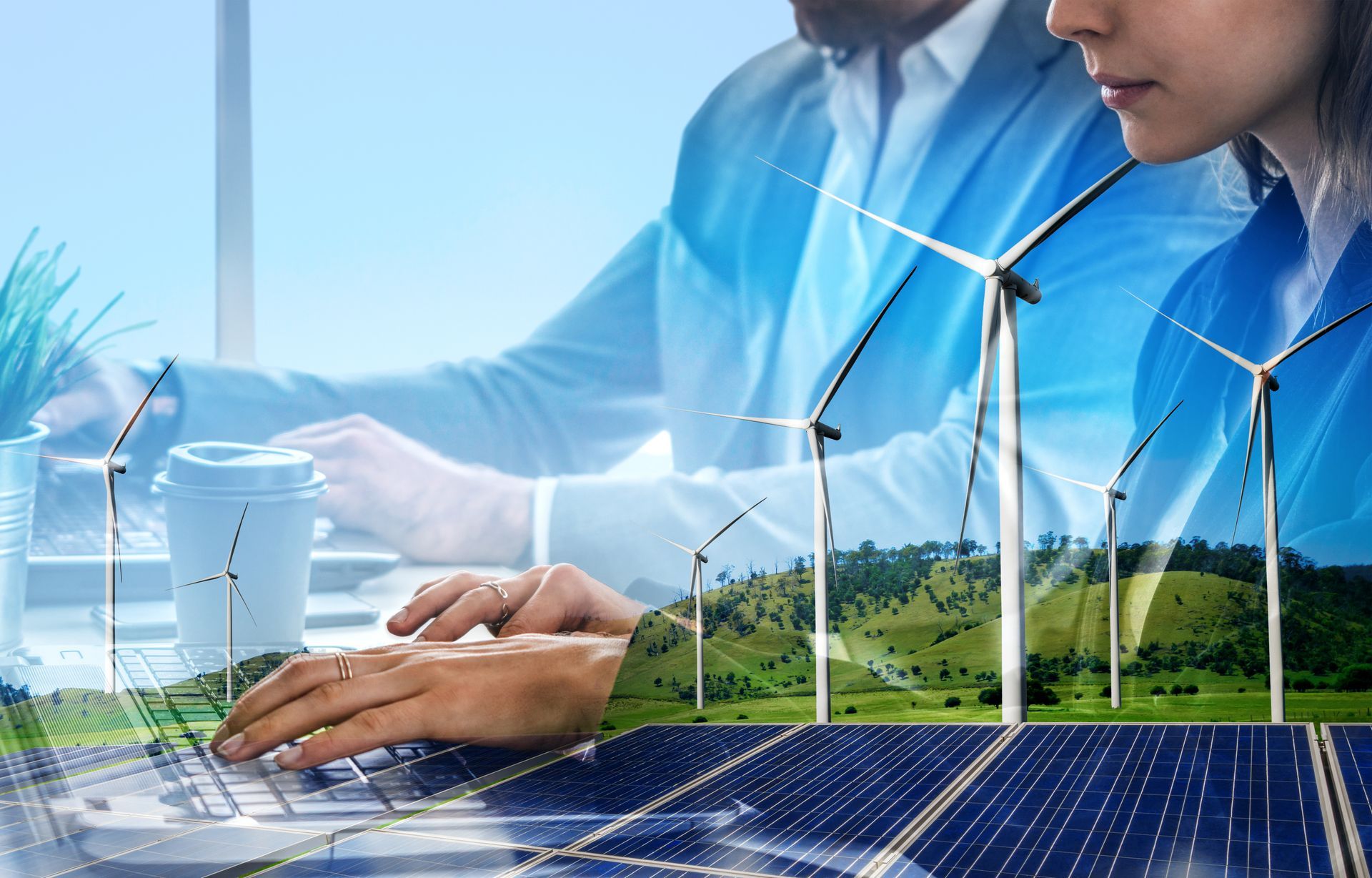 A man and a woman are using a laptop with wind turbines and solar panels in the background.