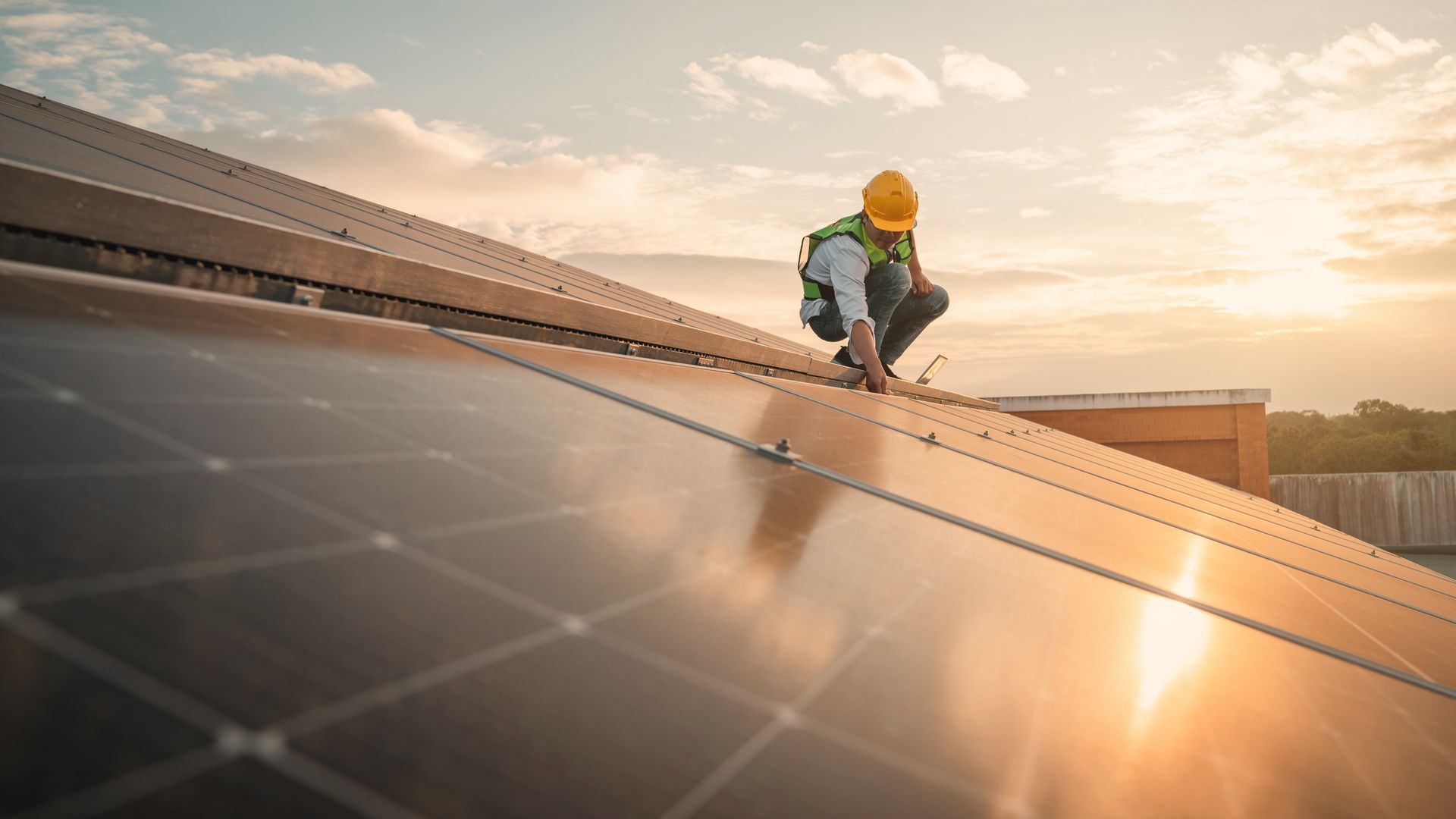 A man is installing solar panels on the roof of a building.