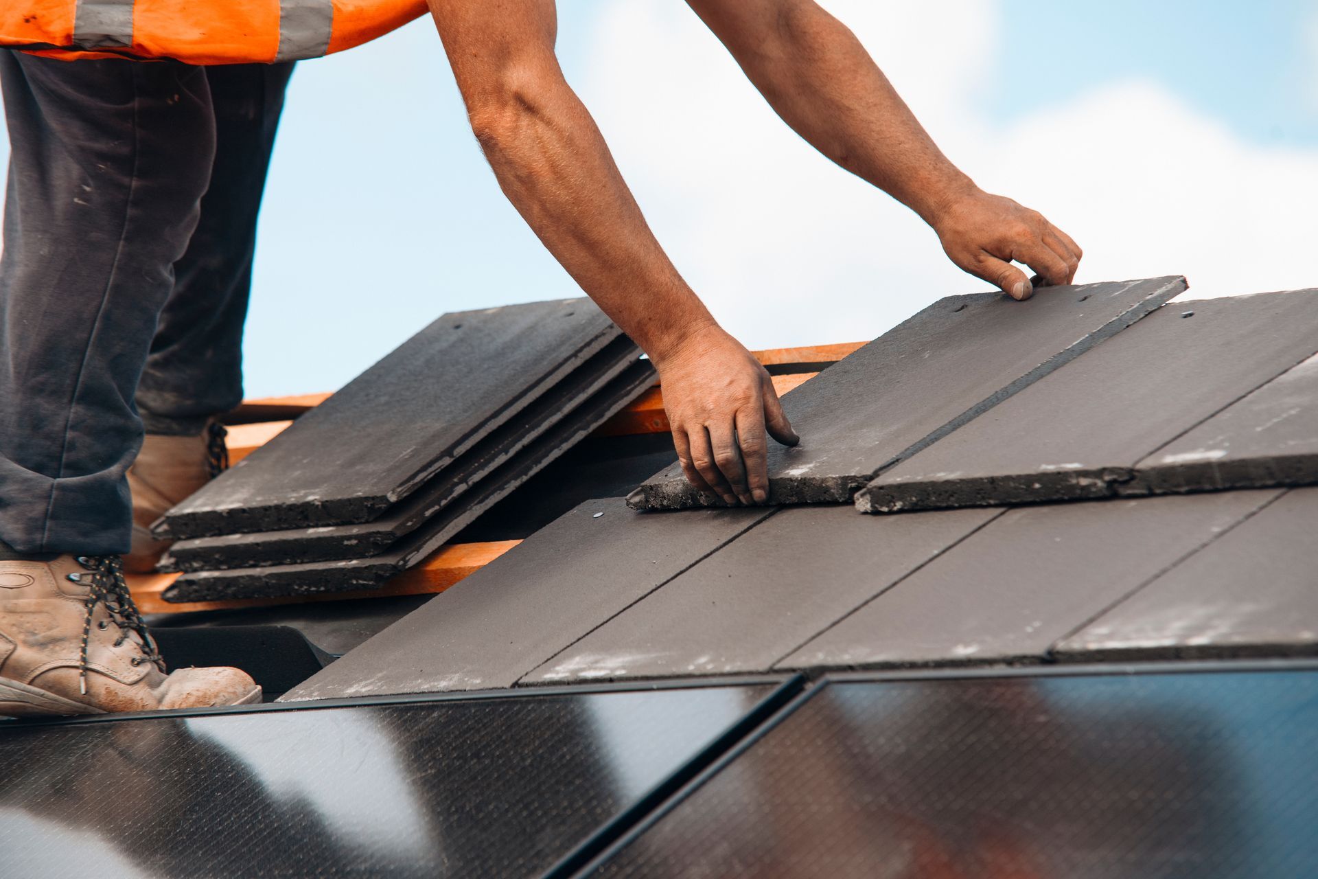 A man is working on a roof with solar panels.