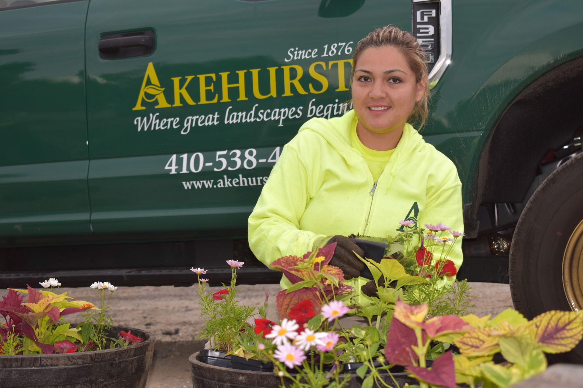 A man is watering plants in a garden with a hose.