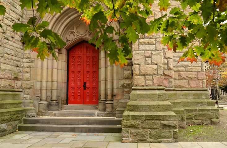 A brick building with a red door and stairs.