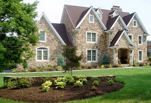 A large stone house with a brown roof and white windows