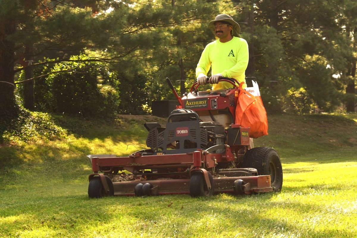 A man is riding a lawn mower on a lush green field.