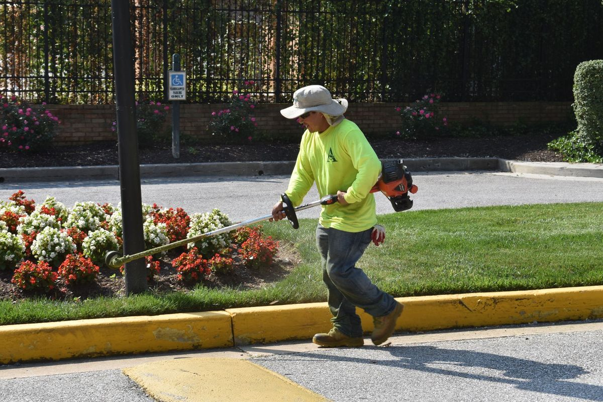 A man in a yellow shirt is cutting grass with a lawn mower.