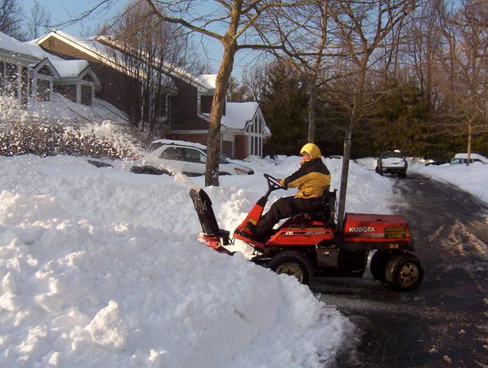 A man is riding a lawn mower through the snow