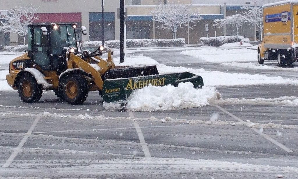 A snow plow is clearing snow from a parking lot