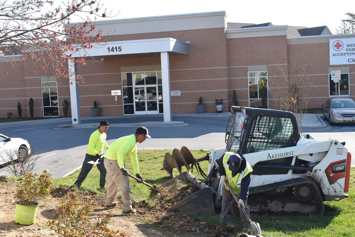 A group of men are working on a lawn in front of a building.