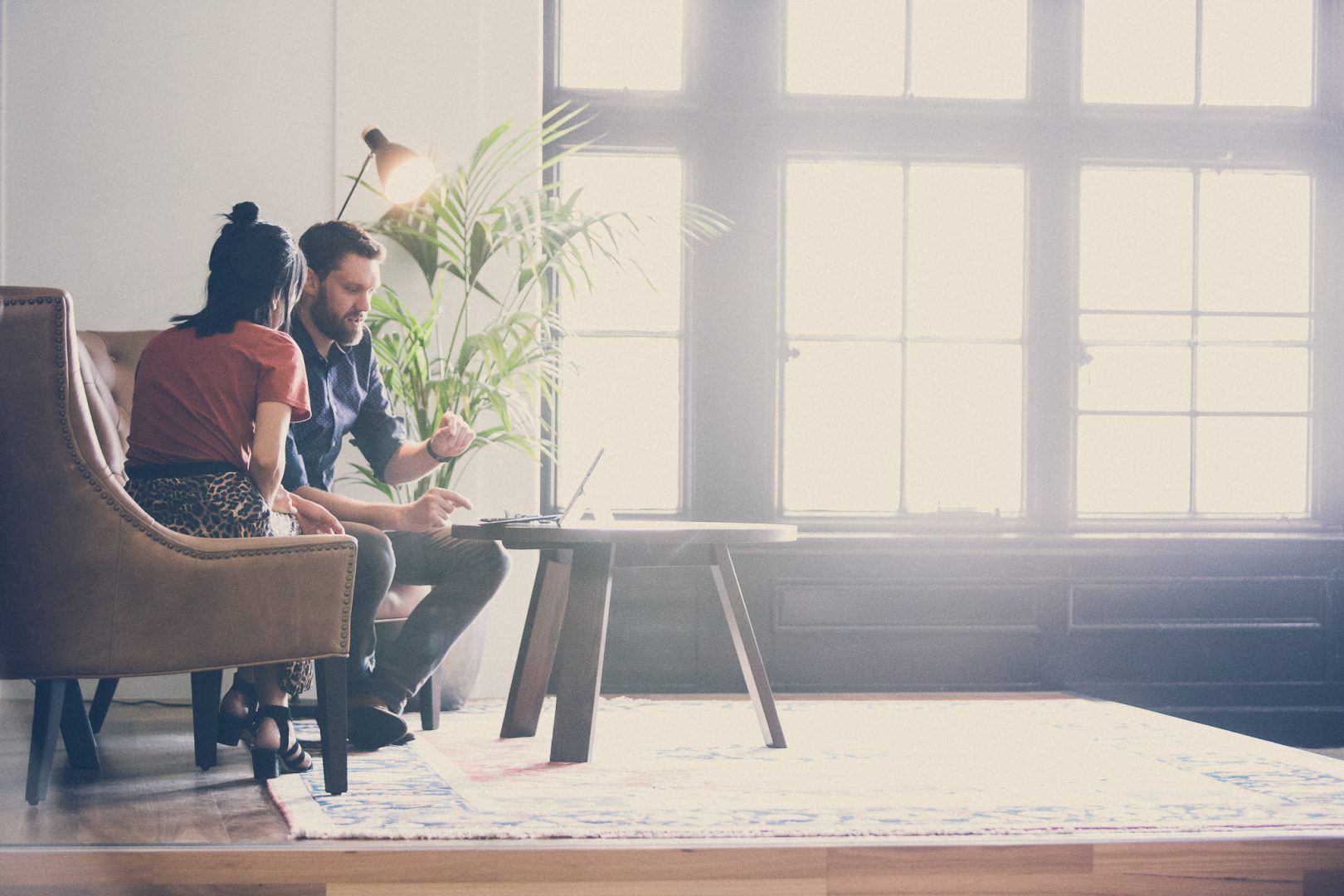 A Man and a Woman are Sitting on a Couch in a Living Room Looking at a Laptop — Search Partners in Melbourne, VIC