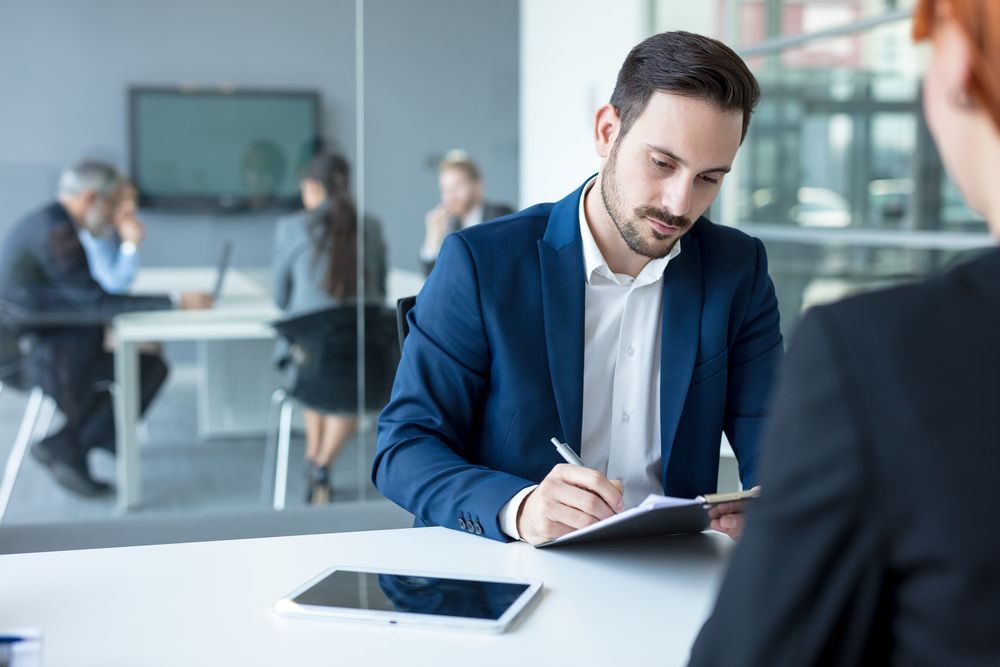 Man in a Blue Suit Taking Notes During an Interview — Search Partners in Melbourne, VIC