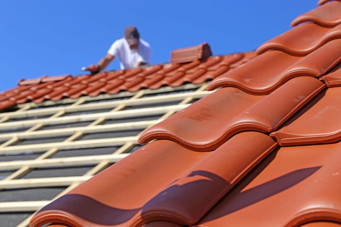 a professional master (roofer) with electric screwdriver covers repairs the roof