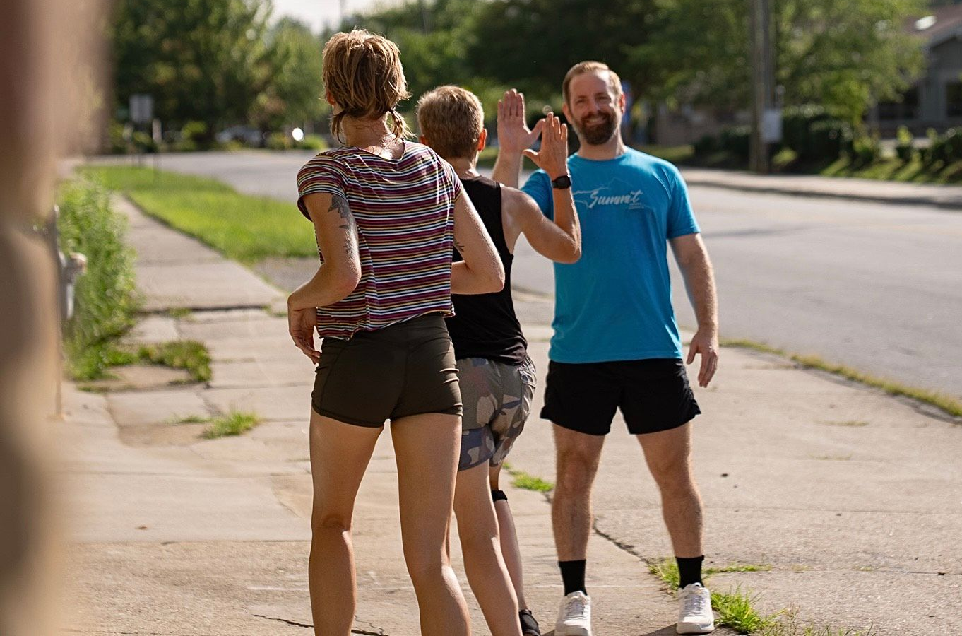 A woman doing a barbell deadlift with a trainer's guidance in a gym in Asheville, NC