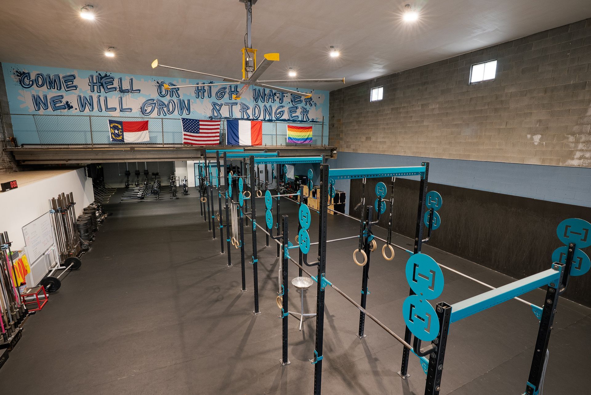 Asheville gym interior with workout equipment, pull-up bars, and flags. Blue and grey tones