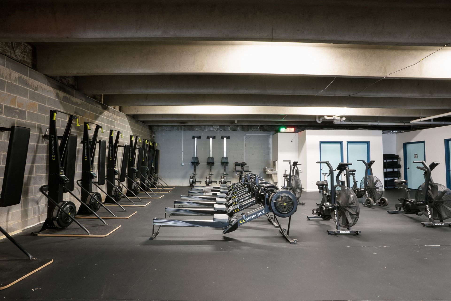 Asheville, gym interior with rows of fitness equipment. Rowing machines, weights, and stationary bikes line the room.