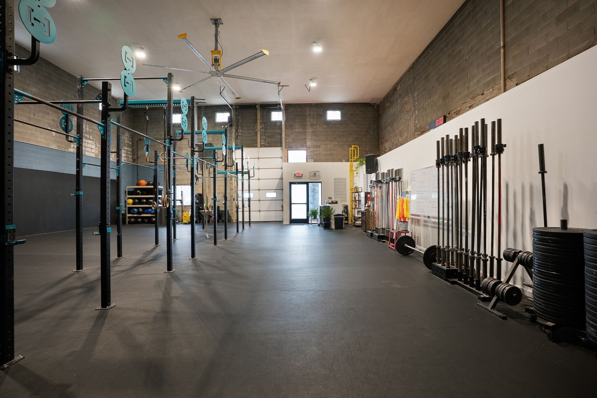 CrossFit gym in Asheville, NC with black equipment, rubber flooring, and exposed brick and white walls.